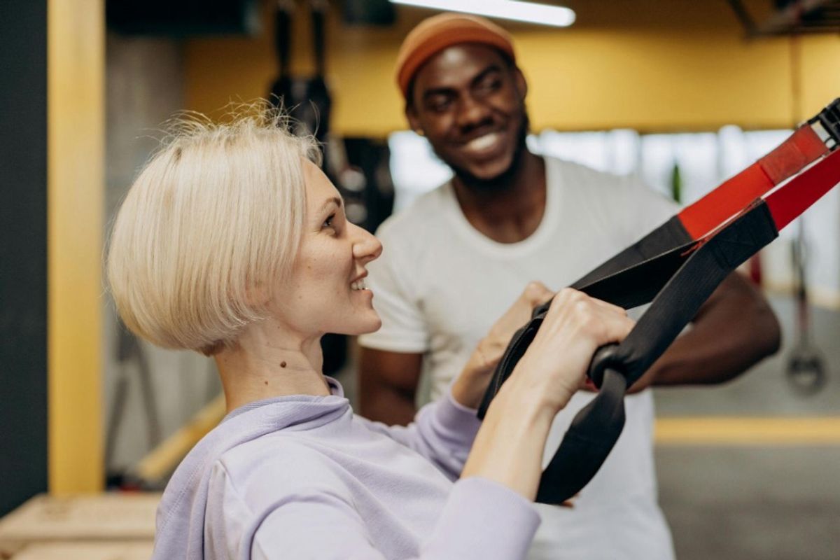 A male personal trainer and his female client in a gym