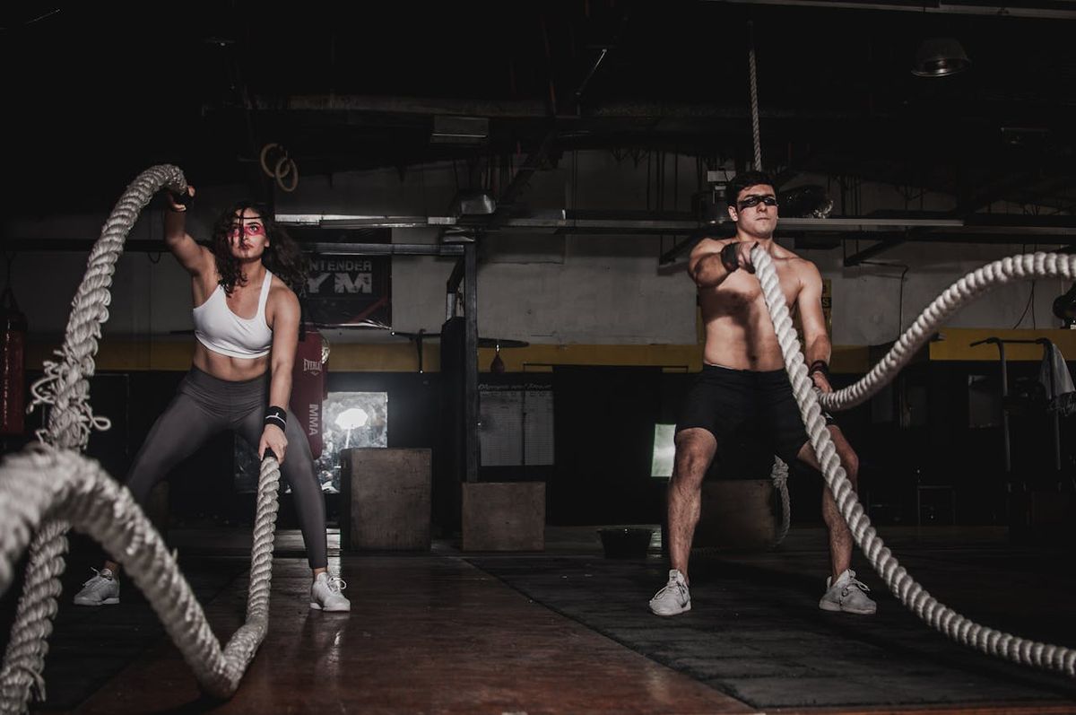 A man and a woman using battle ropes