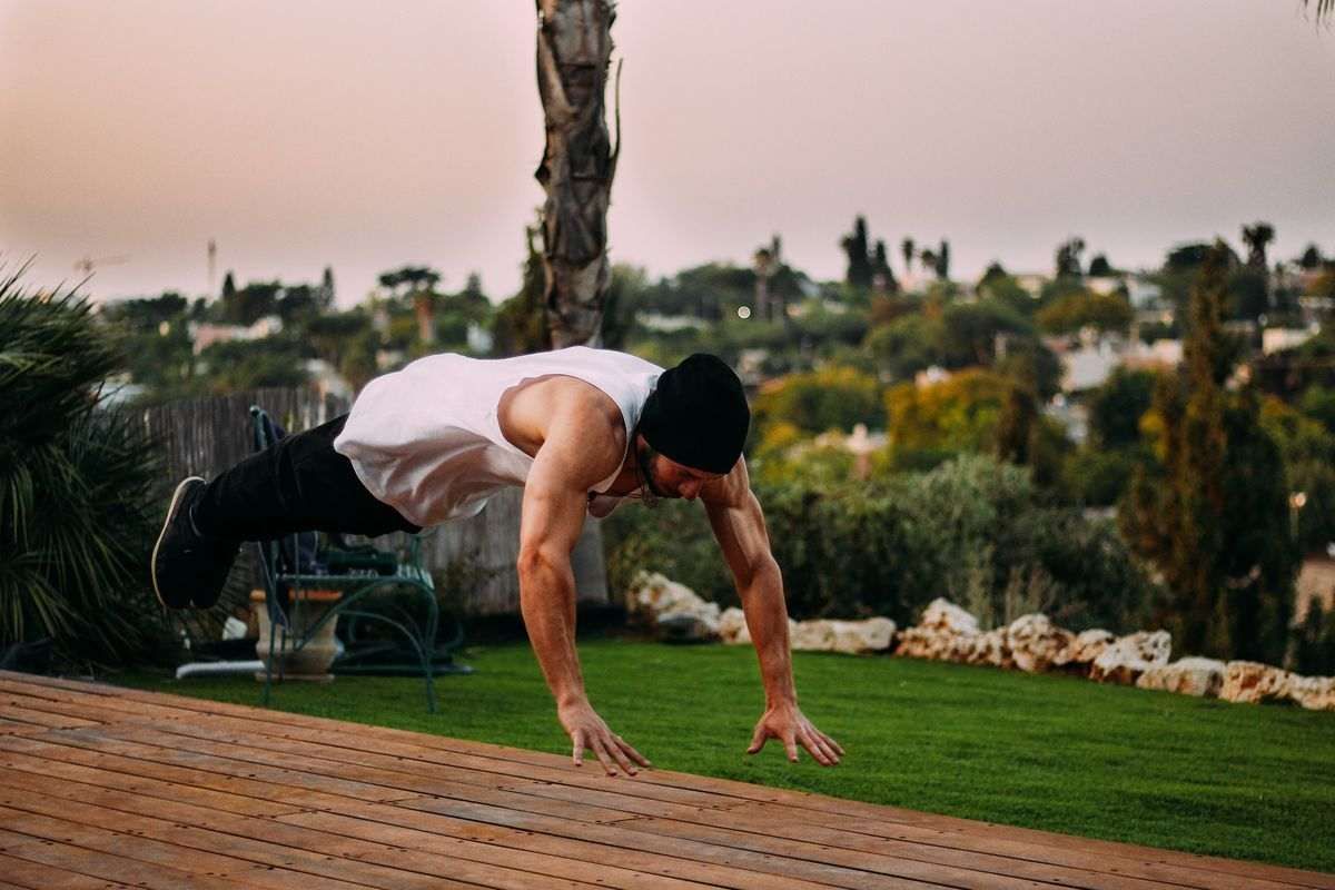 A calisthenics personal trainer doing push-ups. 