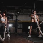 A man and a woman using battle ropes