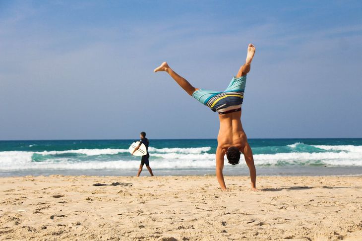 A man doing a handstand on a beacj