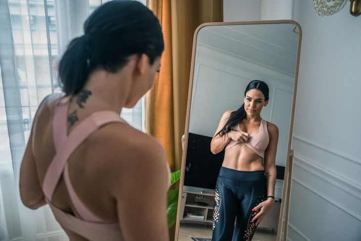 A woman looking at her stomach in the mirror