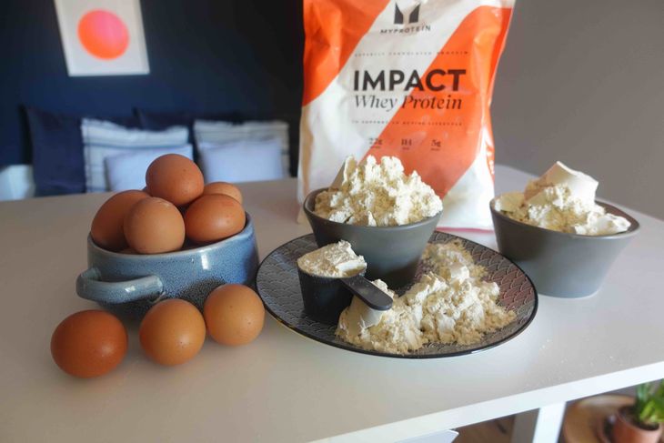 A bowl of eggs and bowls of whey protein powder
