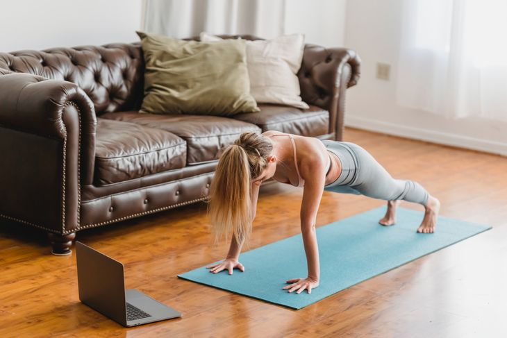 A woman on a yoga mat while personal training from home.