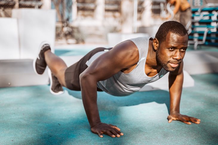 Man doing push ups on the ground as part of a weight loss circuit workout.